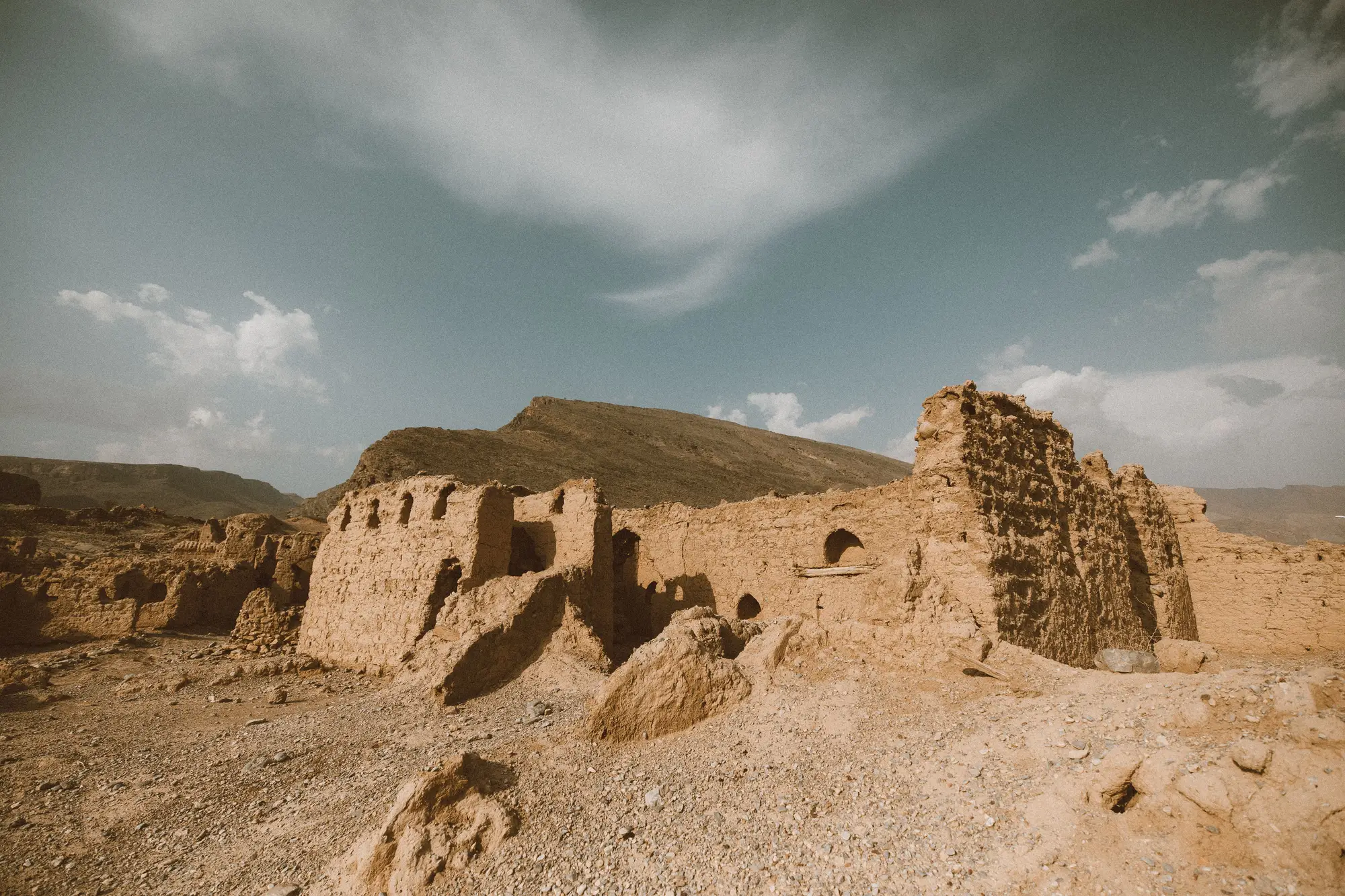 Weathered earthen ruins on open stony ground below a ridge